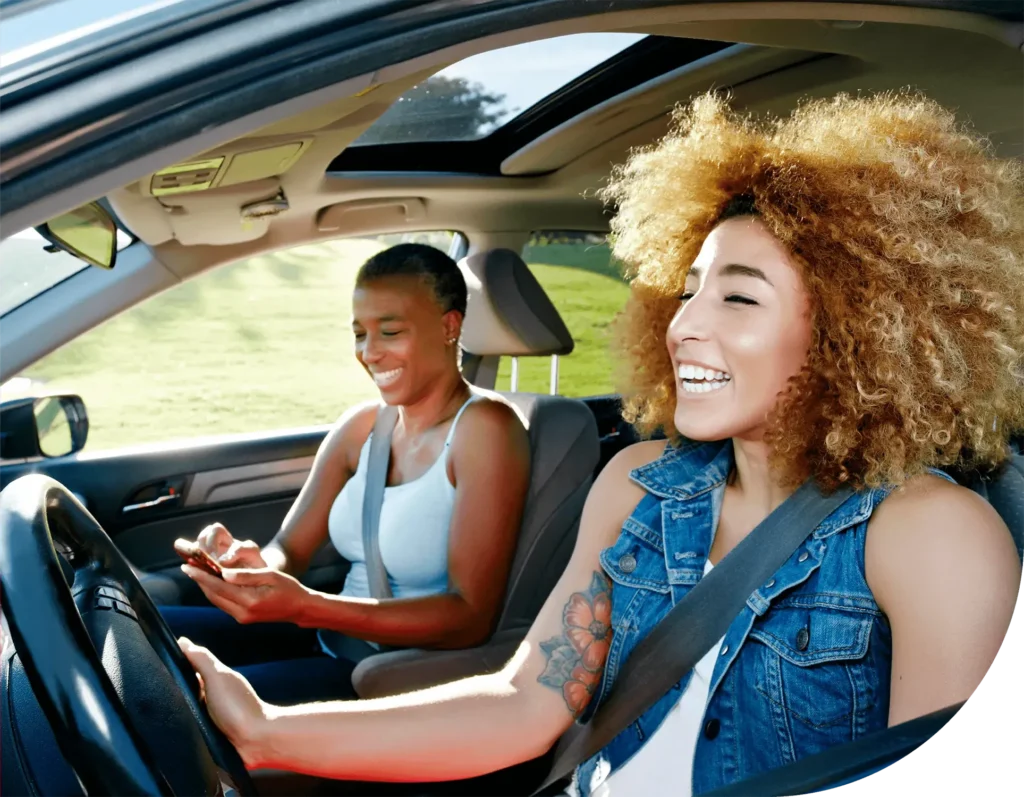 Two happy women sit inside a car
